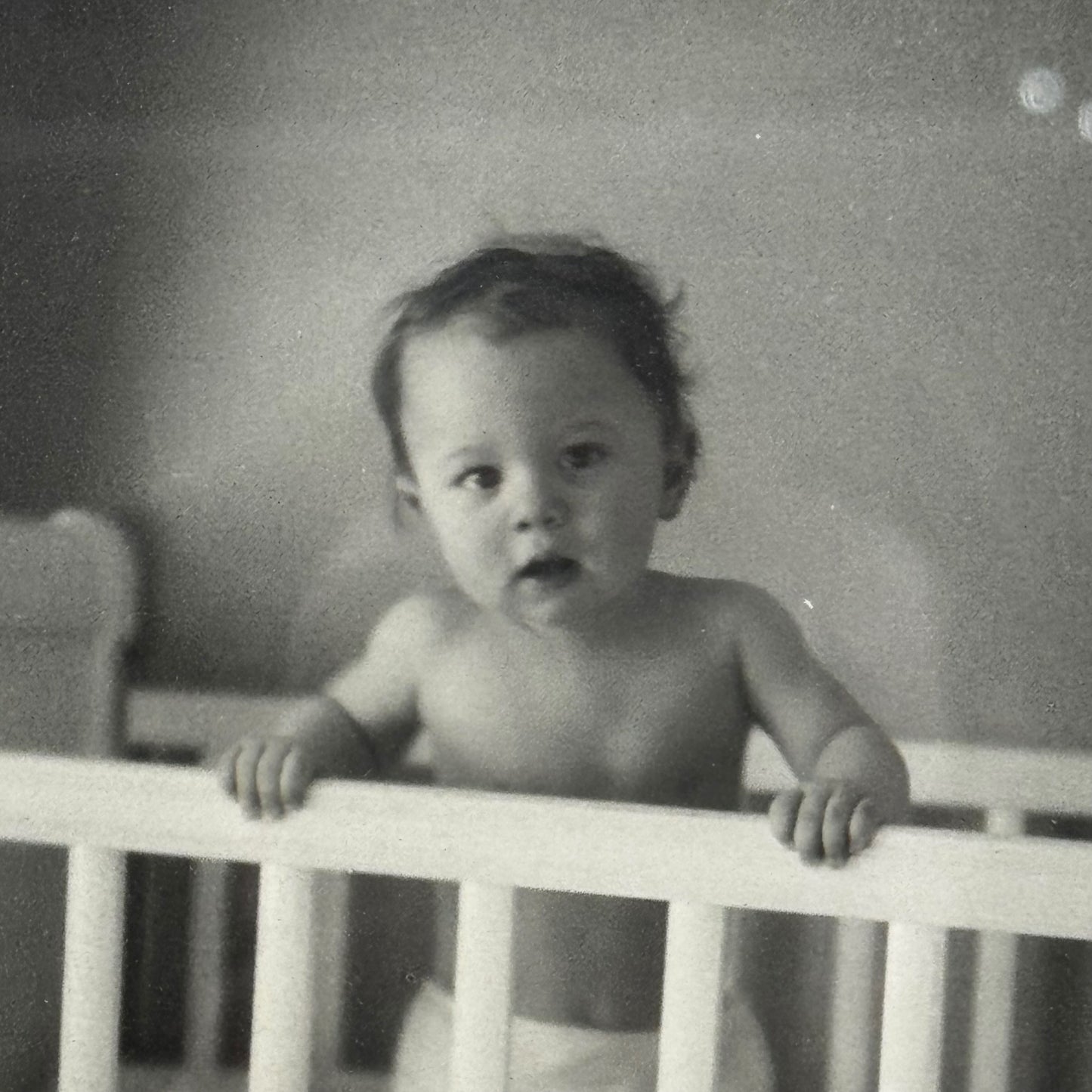 Black and white photo of a baby in a crib