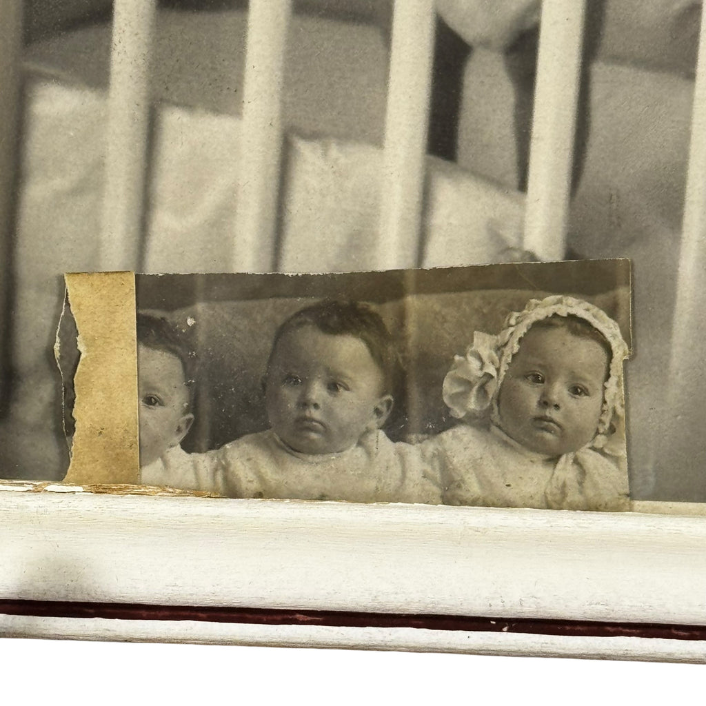 Vintage photograph of two babies in a crib with a distressed border.
