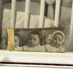 Vintage photograph of two babies in a crib with a distressed border.