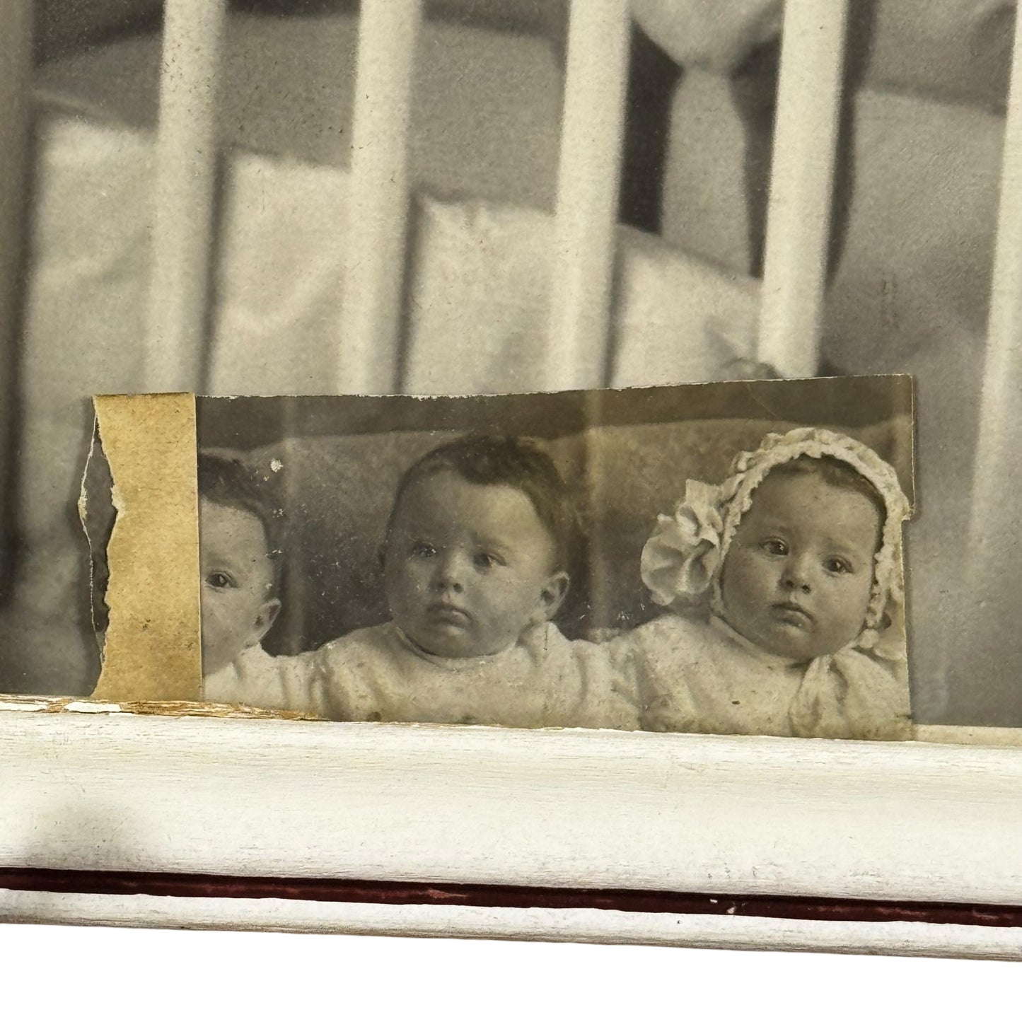 Vintage photograph of two babies in a crib with a distressed border.