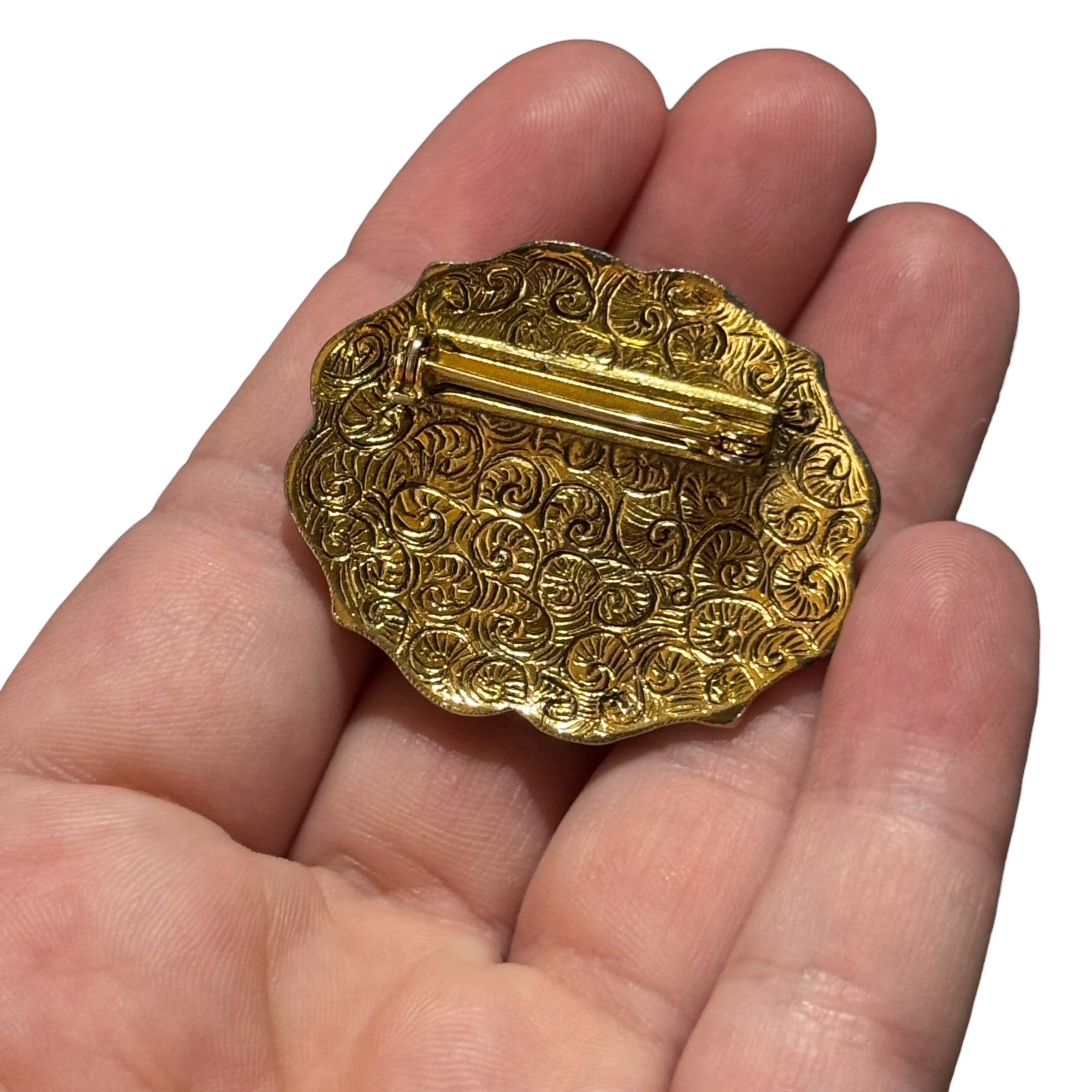 Ornate vintage oval brooch with dark brown gemstone center